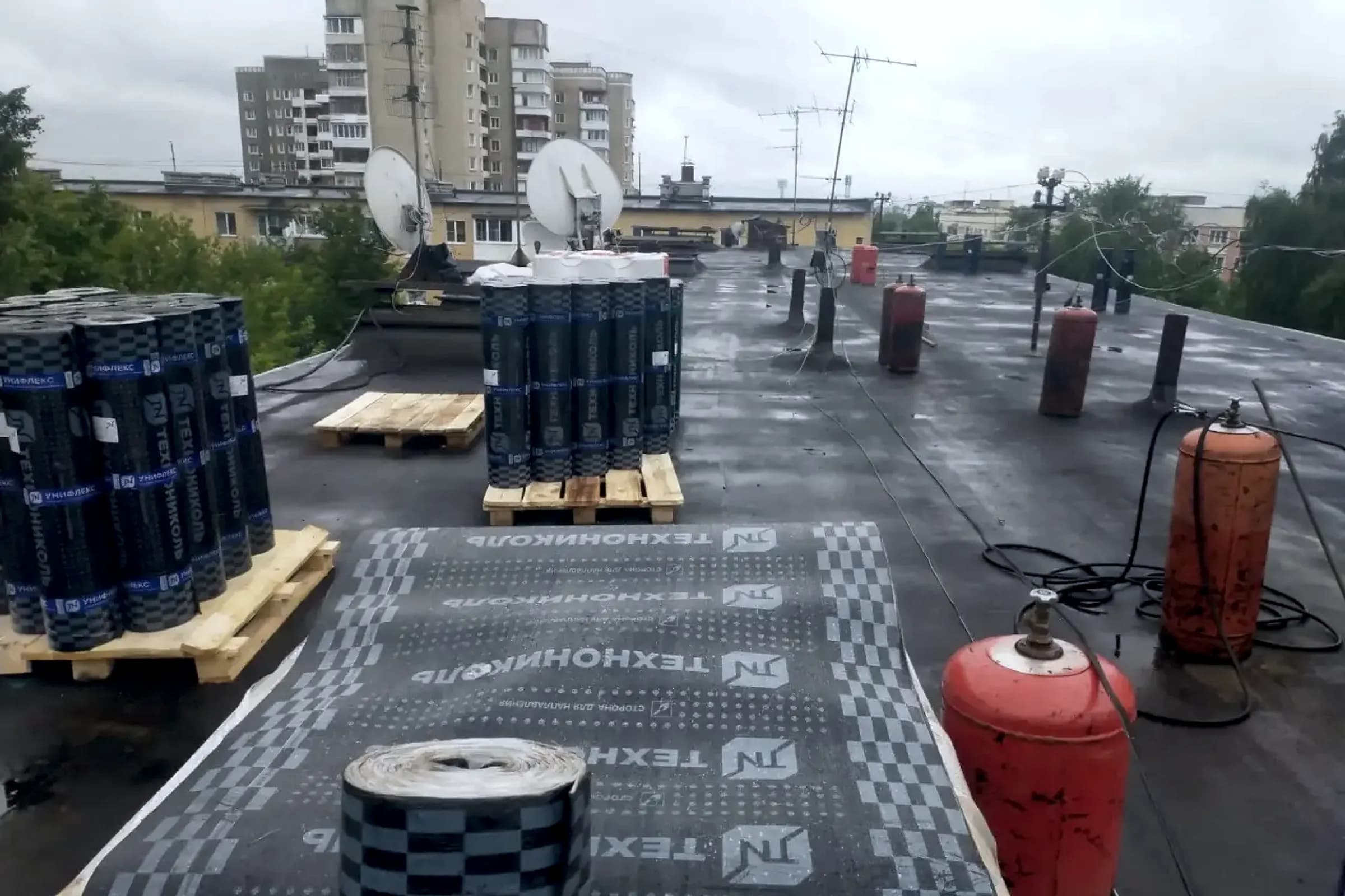 Наплавляемая кровля многоквартирного дома в работе: рулоны и газовые горелки, Тверь